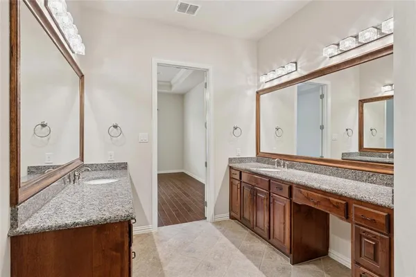 a spacious bathroom with a granite countertop double vanity sink and a mirror