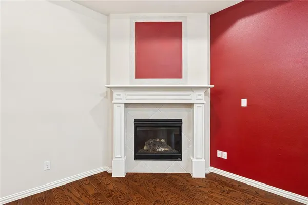 a view of an empty room with wooden floor and a fireplace