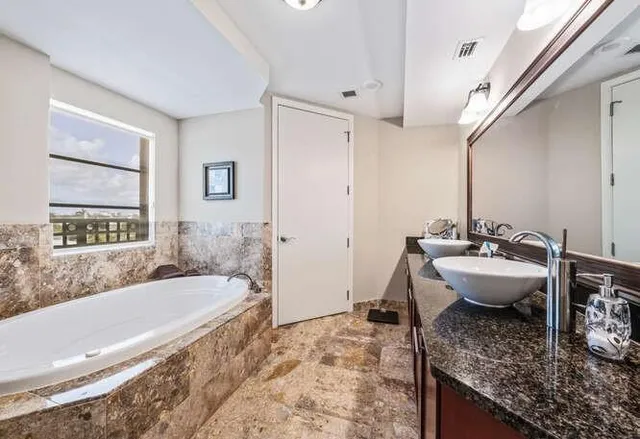 a spacious bathroom with a granite countertop tub sink and mirror