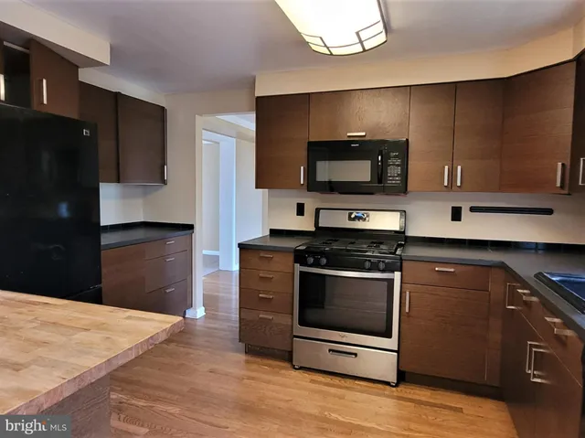 a kitchen with stainless steel appliances kitchen island granite countertop a stove a microwave and a refrigerator
