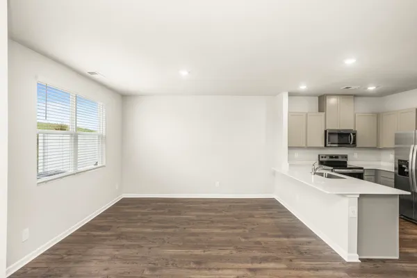 a kitchen with stainless steel appliances a stove top oven a refrigerator a sink and white cabinets with wooden floor