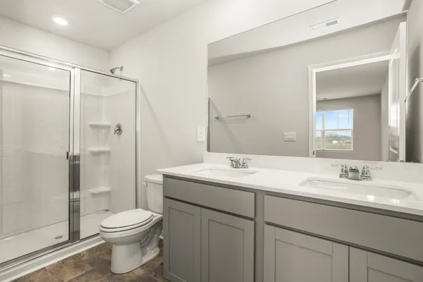 a bathroom with a toilet a sink a glass door a shower and a mirror