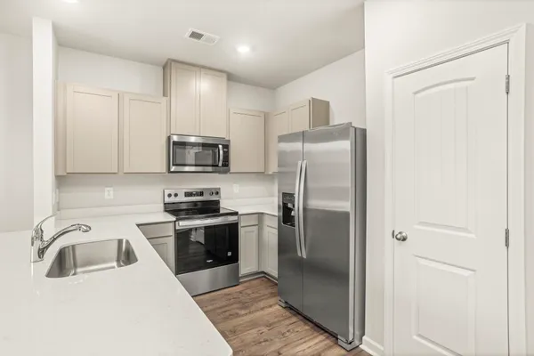 a kitchen with stainless steel appliances granite countertop a refrigerator a stove and a sink with wooden floor