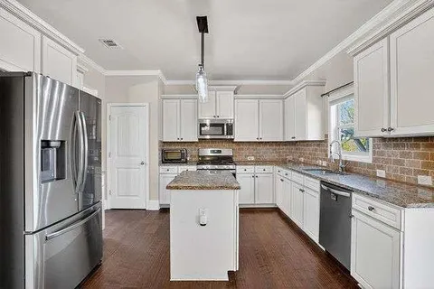 a kitchen with kitchen island white cabinets and stainless steel appliances