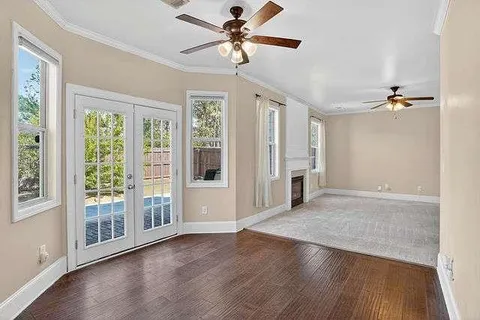 an empty room with wooden floor fan and windows