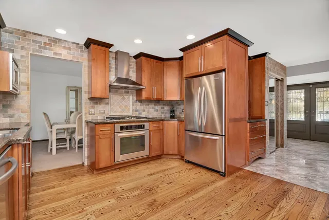 a kitchen with stainless steel appliances granite countertop a refrigerator stove and wooden floor