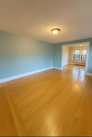 a view of an empty room with window and wooden floor
