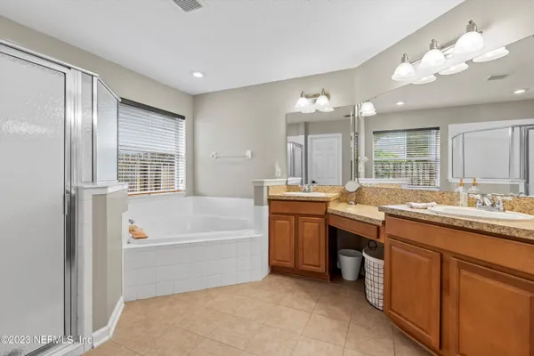 a bathroom with a tub a sink double vanity and a mirror