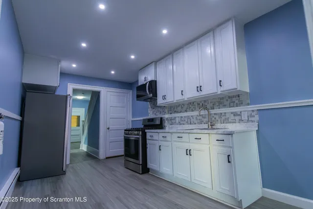 a kitchen with stainless steel appliances granite countertop a refrigerator and a stove top oven