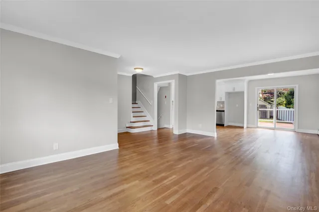 a view of an empty room with wooden floor and window