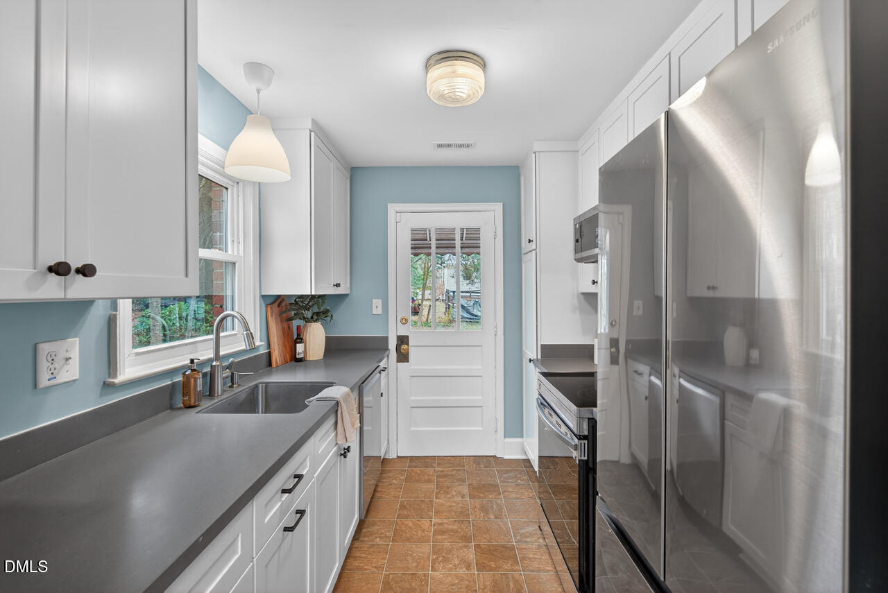 1811 Forest Road Durham, NC 27705 - Photo 9 of 26 a kitchen with a refrigerator a sink and cabinets