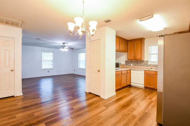 a view of a kitchen with a sink and dishwasher with wooden floor