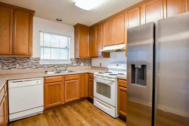 a kitchen with stainless steel appliances granite countertop a refrigerator sink and stove