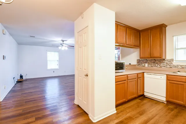 a kitchen with granite countertop a sink cabinets stainless steel appliances and wooden floor