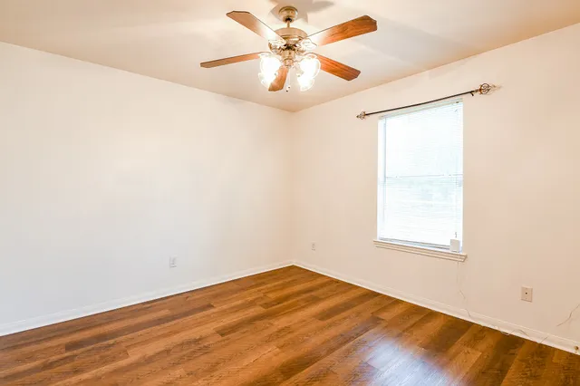 an empty room with a window and a ceiling fan