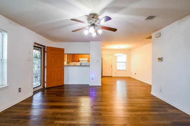 a view of an empty room with window and wooden floor