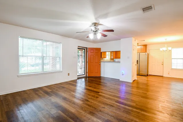 a view of an empty room with window and wooden floor