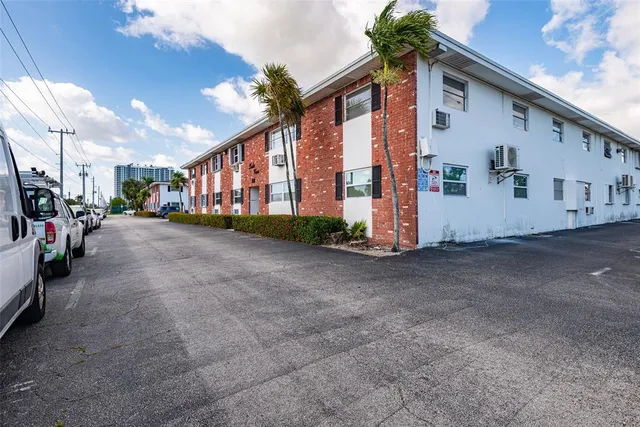 a view of a street with a building and palm trees