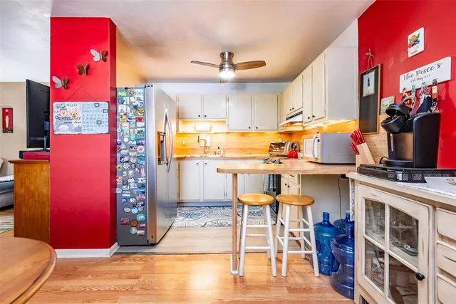 a kitchen with stainless steel appliances kitchen island granite countertop a dining table chairs sink and cabinets