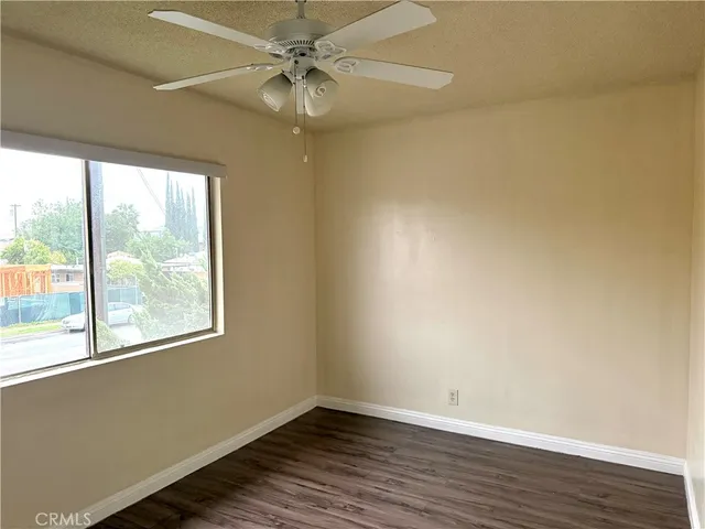 an empty room with wooden floor fan and windows