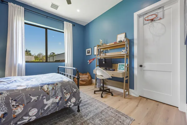 a bedroom with a bed a chair and potted plant on the dresser