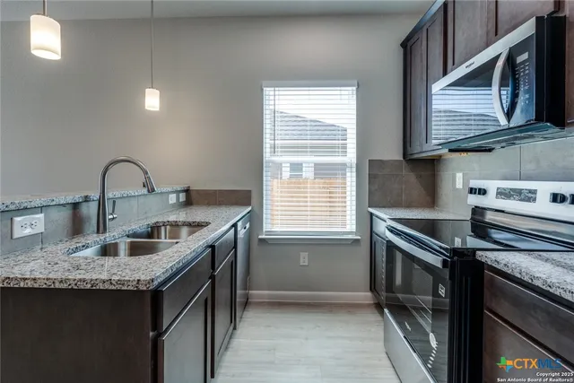 a kitchen with granite countertop a sink stove and cabinets