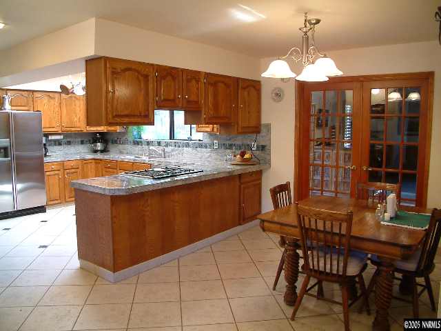 1635 Heitman Court Reno, NV 89509 - Photo 4 of 9 a kitchen with stainless steel appliances granite countertop wooden cabinets a dining table and chairs