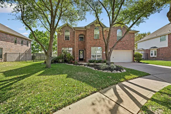 a view of a brick house with a big yard and large trees