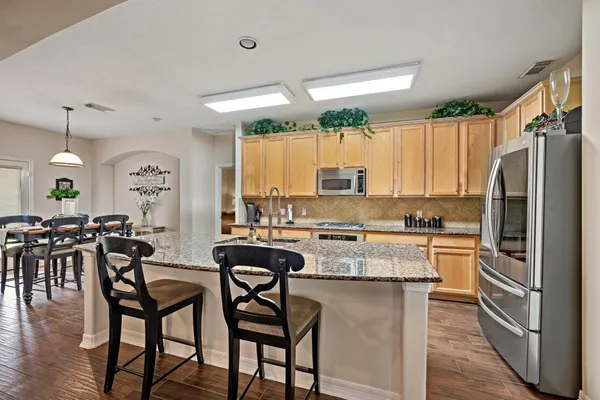 a kitchen with stainless steel appliances granite countertop a sink a stove and a wooden floors