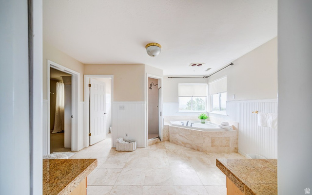 1273 Grayson Court Sandy, UT 84094 - Photo 16 of 27 Spacious bath featuring an inset soaking tub with stone surround, tile flooring, beadboard wainscoting, and large windows