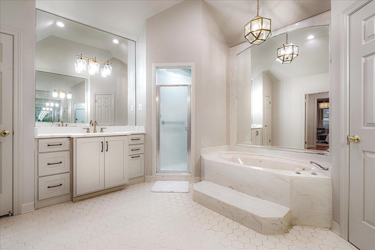 6677 Neshoba Road Memphis, TN 38120 - Photo 27 of 40 a spacious bathroom with a granite countertop sink a large mirror a bathtub and shower
