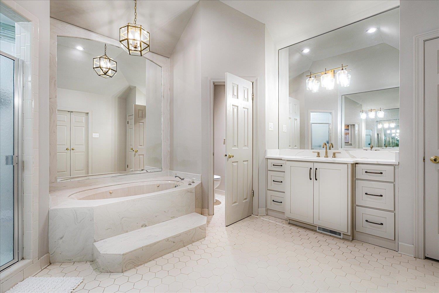 6677 Neshoba Road Memphis, TN 38120 - Photo 28 of 40 a spacious bathroom with a double vanity sink a mirror a bathtub and shower