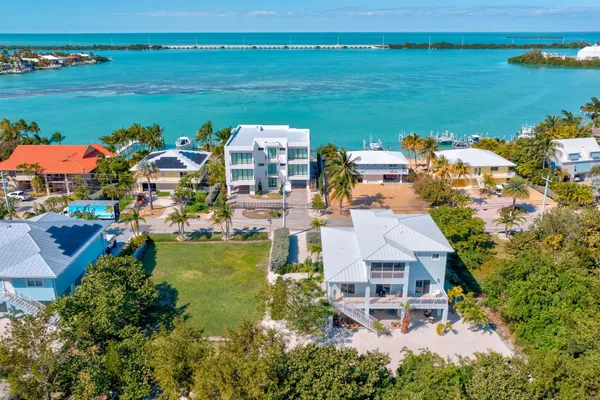 an aerial view of ocean and residential houses with outdoor space
