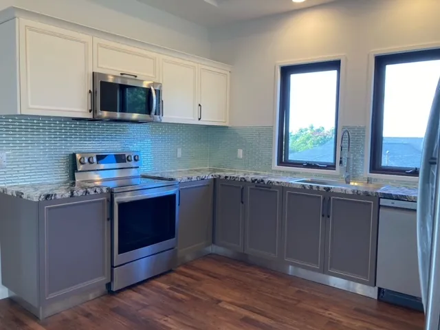 a kitchen with stainless steel appliances granite countertop a stove a sink and a microwave