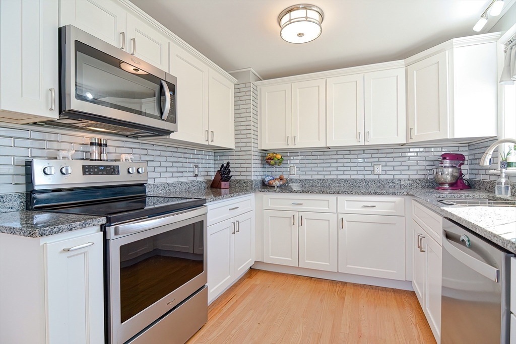 41 Kenyon Road Tiverton, RI 02878 - Photo 8 of 38 a kitchen with stainless steel appliances white cabinets granite counter tops and a wooden floors