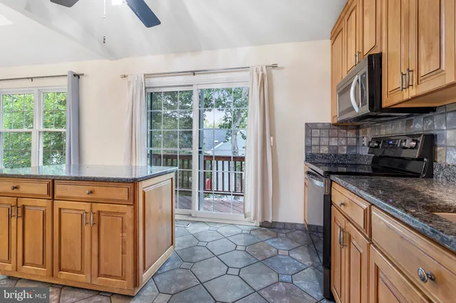 a kitchen with stainless steel appliances granite countertop a refrigerator a stove and a sink