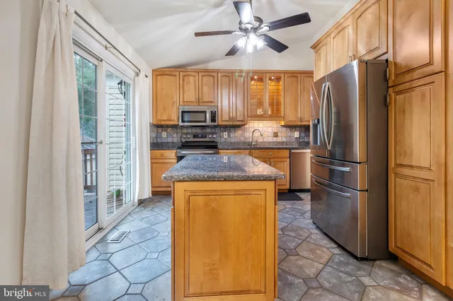 a kitchen with stainless steel appliances granite countertop a refrigerator a stove top oven and a sink