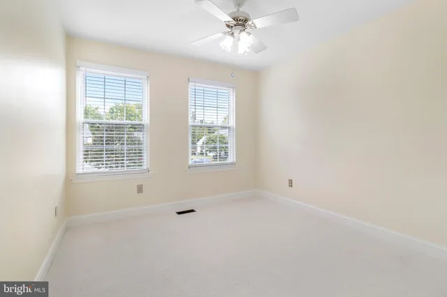 an empty room with a ceiling fan and window