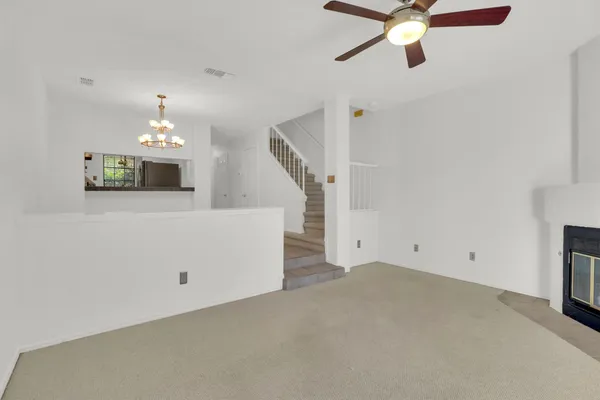 an empty room with a chandelier fan and wooden floor