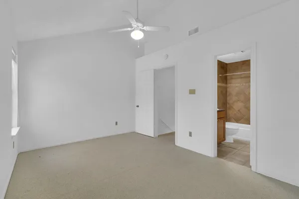 an empty room with a ceiling fan and bathroom