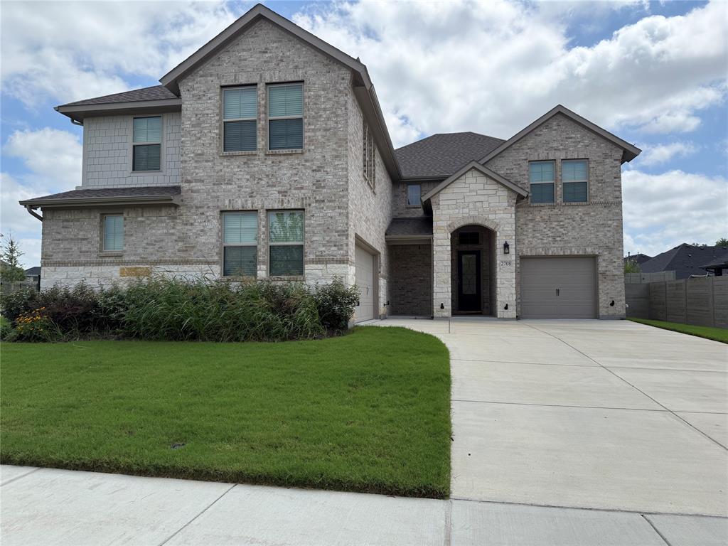 2708 Andesite Road McKinney, TX 75071 - Photo 2 of 35 Two-story residence featuring a brick and stone facade with gabled rooflines, an arched entryway, and dual garage doors