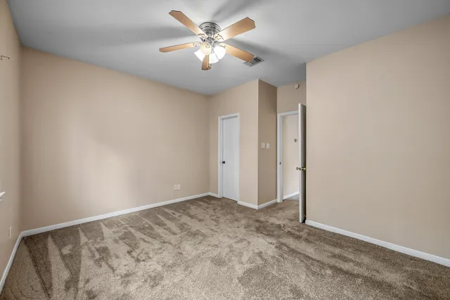 a view of a big room with windows and chandelier fan