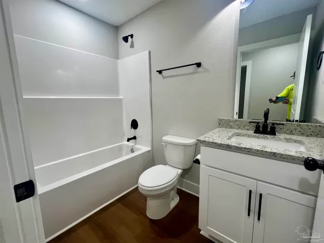 a bathroom with a granite countertop sink toilet mirror and shower