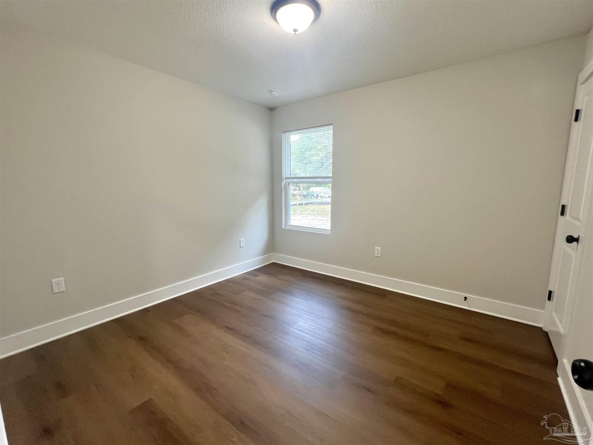 4417 Oak Lane Milton, FL 32583 - Photo 14 of 24 an empty room with wooden floor and windows