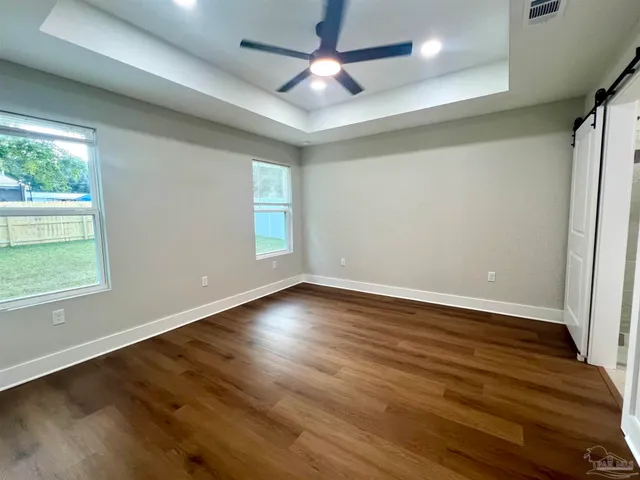 an empty room with wooden floor chandelier fan and windows