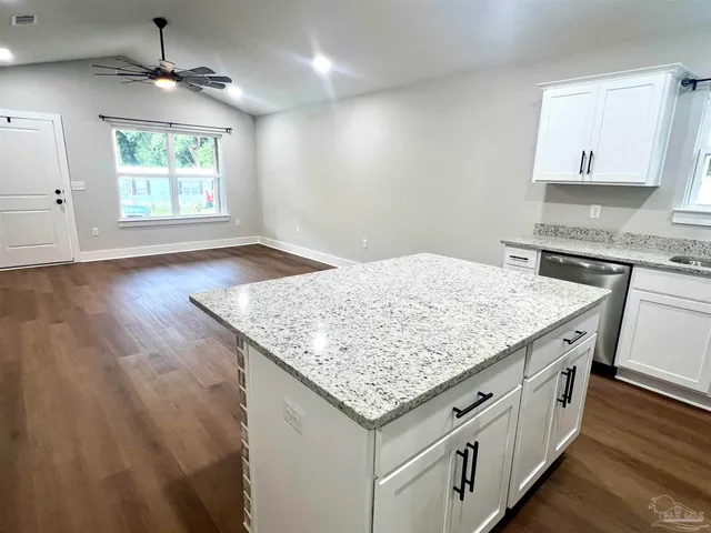 an open kitchen with granite countertop white cabinets and a wooden floor