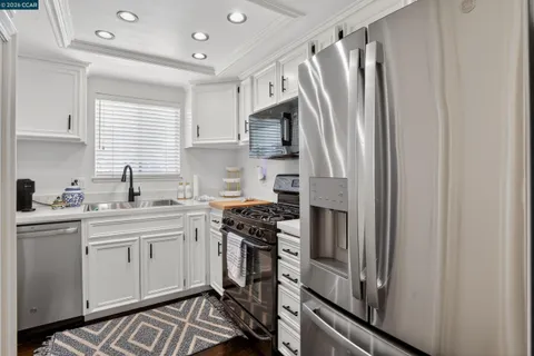 a kitchen with stainless steel appliances a refrigerator sink and white cabinets
