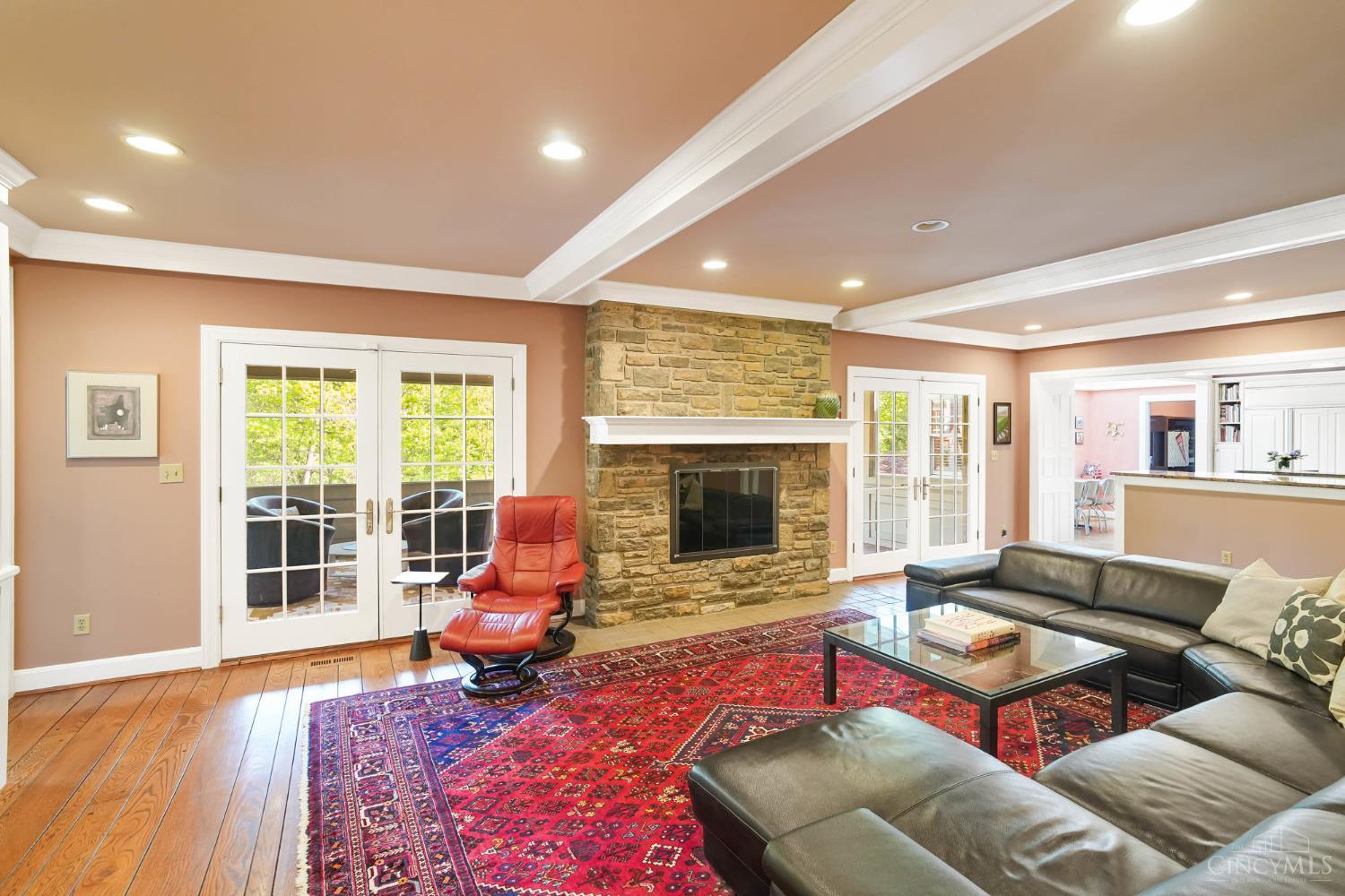 2780 Walsh Road Cincinnati, OH 45208 - Photo 3 of 68 This warm and inviting family room is designed for everyday living and effortless entertaining—anchored by a striking stone fireplace and framed by rich hardwood floors and classic millwork. The generously scaled layout offers multiple seating areas, seamless flow to adjacent spaces and French doors that invite in natural light while opening to outdoor living. Custom built-ins add both function and charm, completing this comfortable yet refined gathering space.