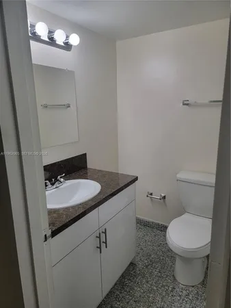 a bathroom with a granite countertop sink toilet and a mirror