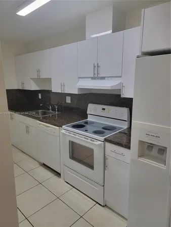 a kitchen with granite countertop white cabinets and white appliances